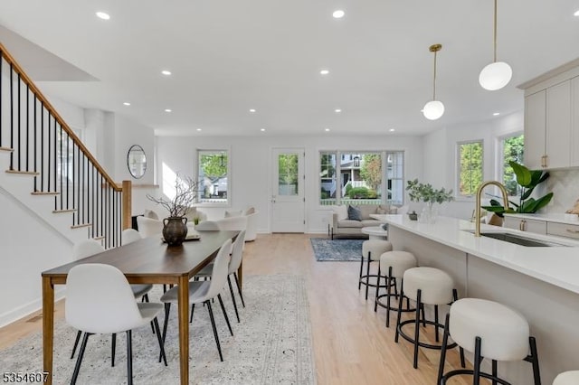 dining area featuring light wood-style floors, healthy amount of natural light, recessed lighting, stairs, and baseboards