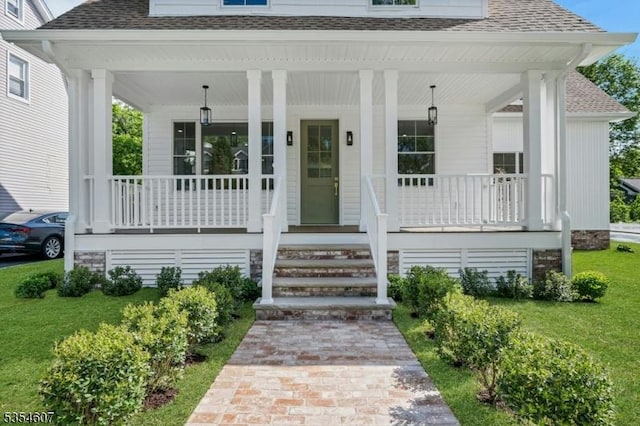 property entrance with a shingled roof, covered porch, and a yard
