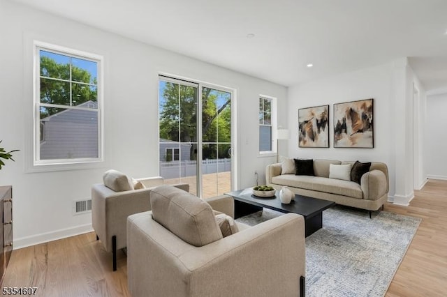 living room with light wood-style floors, baseboards, and recessed lighting