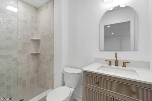 full bathroom featuring toilet, a tile shower, and vanity