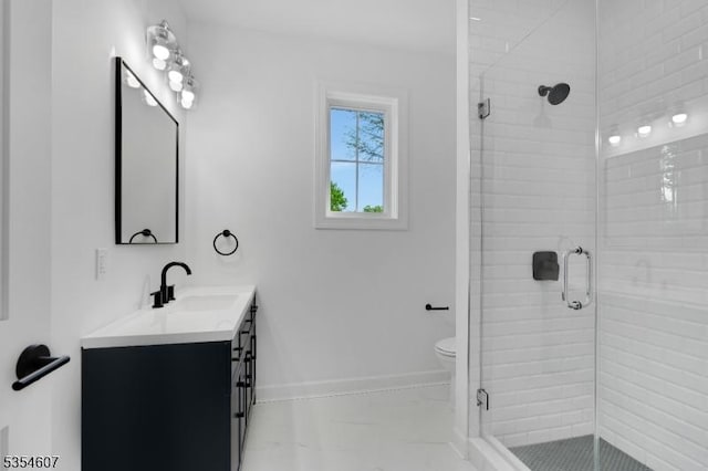 bathroom with a stall shower, vanity, baseboards, and toilet