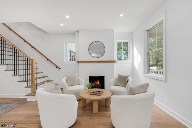 sitting room featuring stairs, a lit fireplace, recessed lighting, light wood-style floors, and baseboards