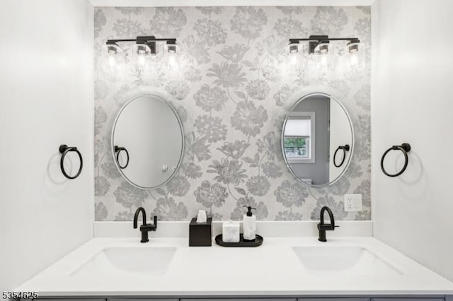 bathroom featuring double vanity, wallpapered walls, and a sink