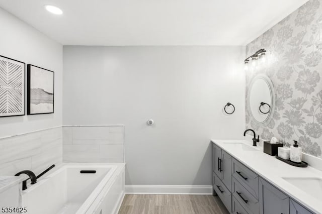 bathroom with a sink, a bath, wallpapered walls, and double vanity