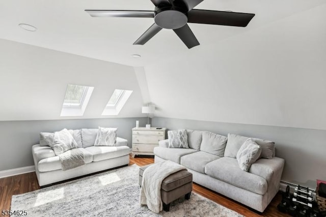 living room featuring vaulted ceiling with skylight, baseboards, a ceiling fan, and wood finished floors