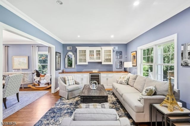living area featuring indoor wet bar, beverage cooler, a healthy amount of sunlight, and wood finished floors
