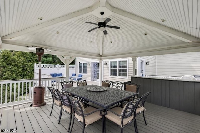 wooden deck with outdoor dining area and ceiling fan