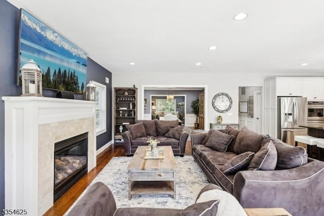 living room featuring recessed lighting, a glass covered fireplace, and wood finished floors