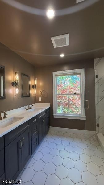 full bath featuring a sink, tile patterned floors, a stall shower, and double vanity