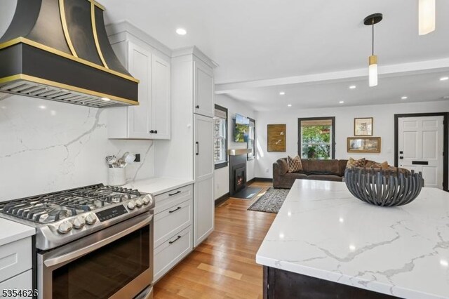 kitchen with custom exhaust hood, light wood-type flooring, open floor plan, and gas range