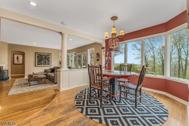 dining area with baseboards, ornate columns, recessed lighting, light wood finished floors, and a notable chandelier