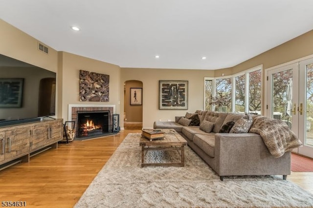 living area featuring visible vents, arched walkways, a healthy amount of sunlight, and light wood-type flooring