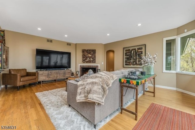 living area with arched walkways, light wood-style flooring, recessed lighting, baseboards, and visible vents