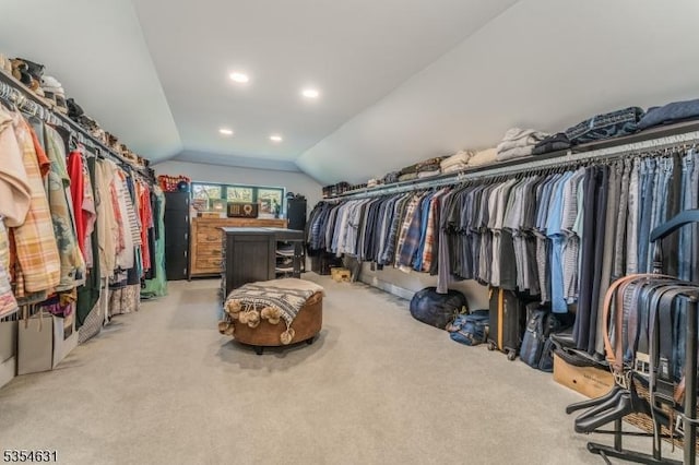 walk in closet with light colored carpet and lofted ceiling