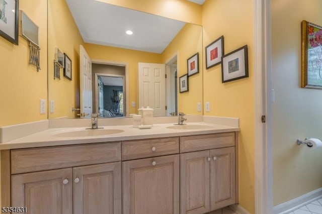 bathroom featuring double vanity, a sink, and baseboards