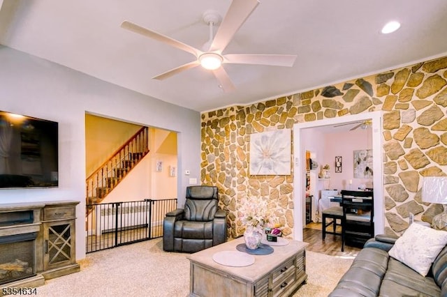 living area with a ceiling fan and stairs