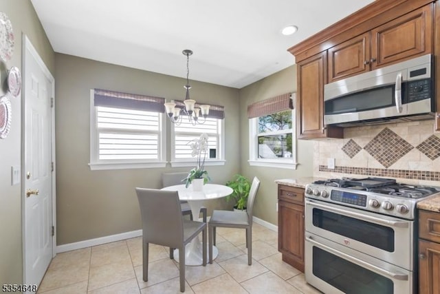 kitchen with brown cabinetry, tasteful backsplash, baseboards, a chandelier, and stainless steel appliances