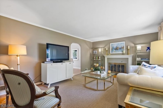living area featuring carpet flooring, a fireplace, arched walkways, baseboards, and ornamental molding