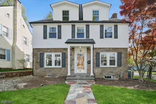 view of front of property with a chimney, a front lawn, and stone siding