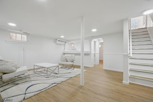 basement featuring stairs, arched walkways, recessed lighting, and wood finished floors