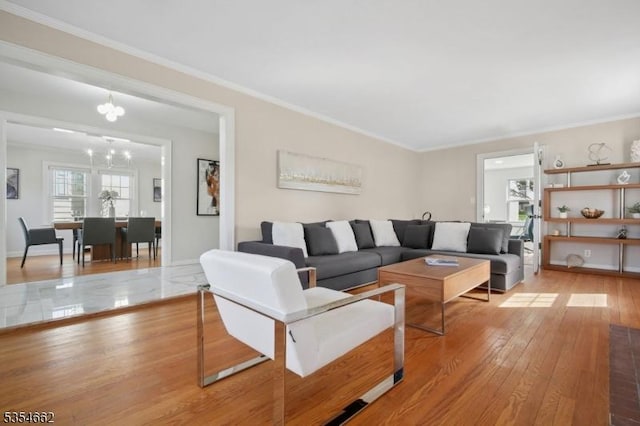 living area featuring ornamental molding, light wood finished floors, and a chandelier