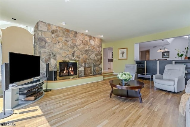 living area with a fireplace, a chandelier, and wood finished floors