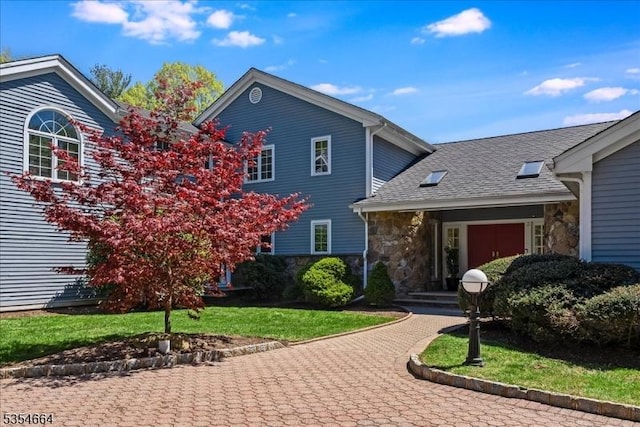 view of front facade featuring stone siding, a shingled roof, and a front lawn