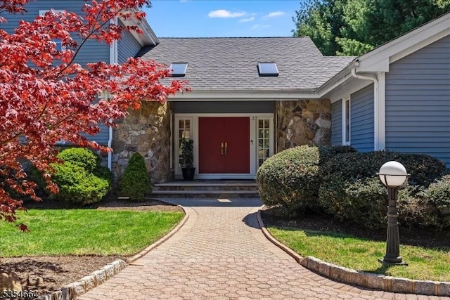 view of exterior entry featuring stone siding and roof with shingles