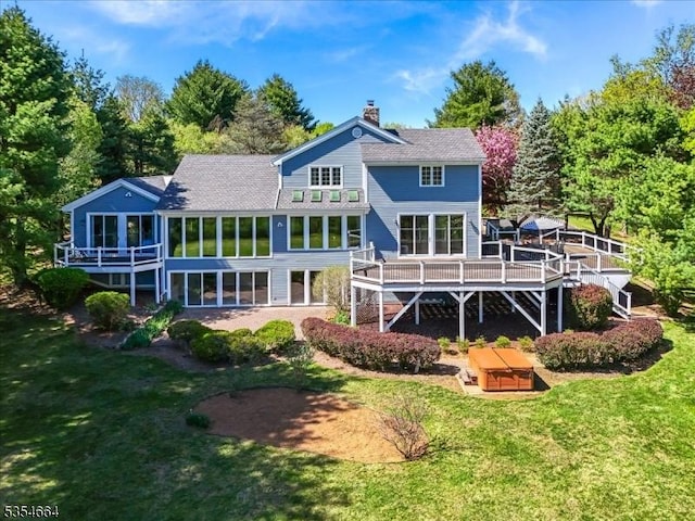 rear view of property featuring a yard, a wooden deck, and a chimney