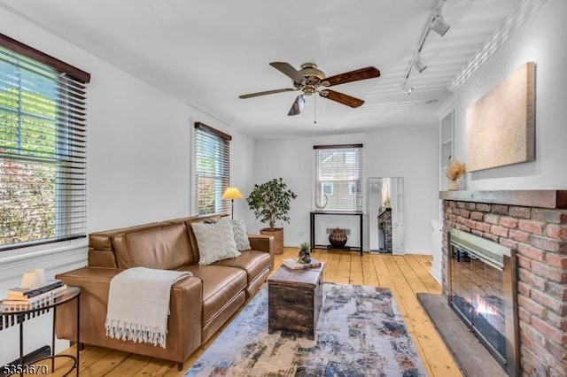 living room featuring wood-type flooring, a ceiling fan, track lighting, and a fireplace