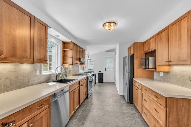 kitchen with a sink, appliances with stainless steel finishes, backsplash, and light countertops