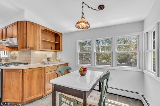 kitchen featuring a healthy amount of sunlight, baseboard heating, light tile patterned floors, stainless steel gas range, and under cabinet range hood