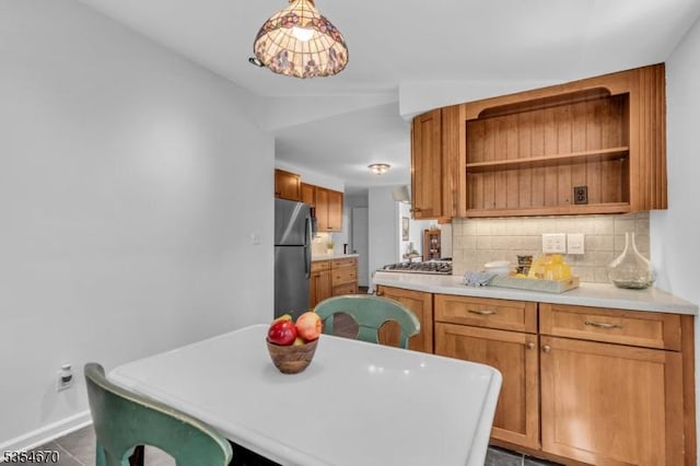 kitchen with brown cabinetry, open shelves, light countertops, backsplash, and stainless steel appliances