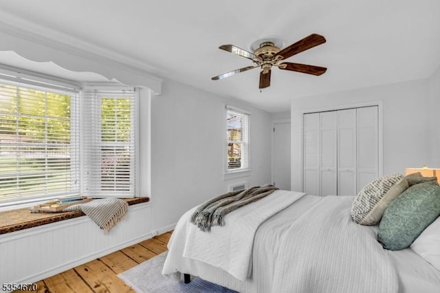 bedroom featuring light wood-style floors, multiple windows, a ceiling fan, and a closet