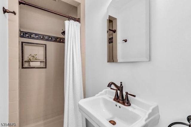 full bath featuring tiled shower and a sink