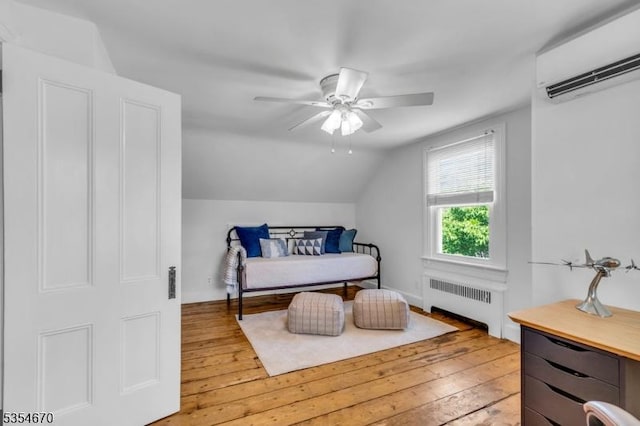bedroom with a wall mounted air conditioner, radiator heating unit, hardwood / wood-style flooring, a ceiling fan, and vaulted ceiling