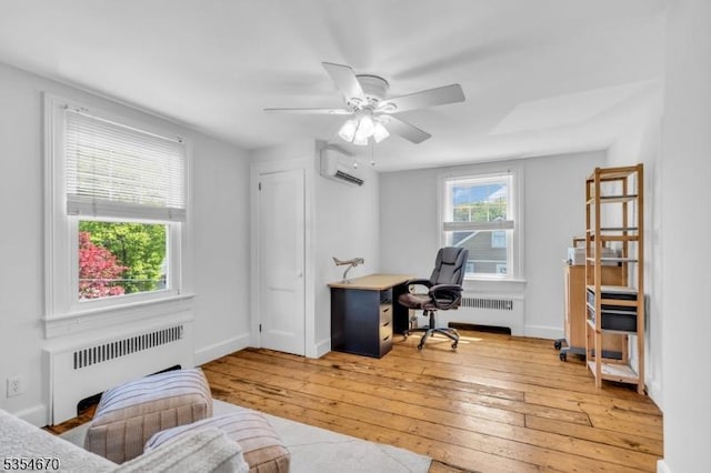 home office featuring a wall mounted air conditioner, light wood-style flooring, a ceiling fan, and radiator heating unit