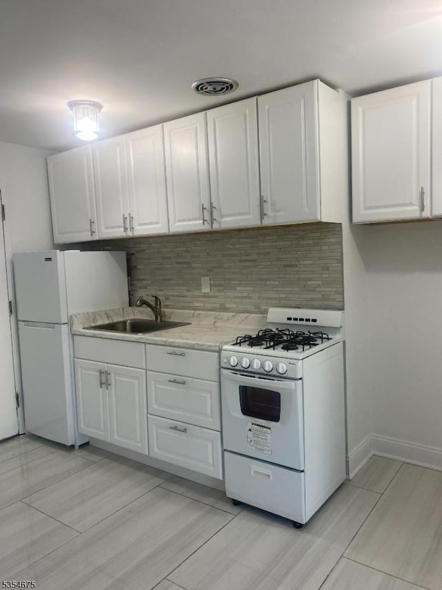 kitchen featuring a sink, white cabinets, white appliances, and tasteful backsplash