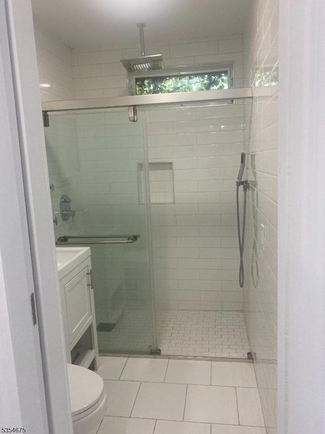 bathroom featuring vanity, toilet, tile patterned floors, and a stall shower