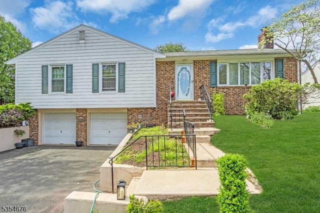 view of front of property with brick siding, asphalt driveway, a garage, a front yard, and a chimney