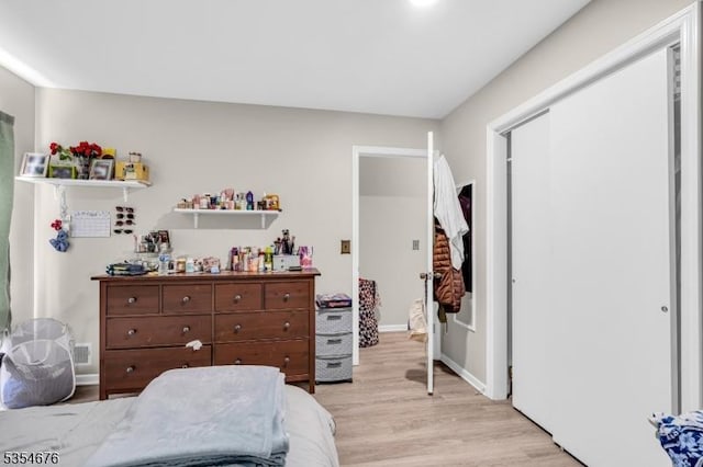 bedroom with light wood finished floors and a closet