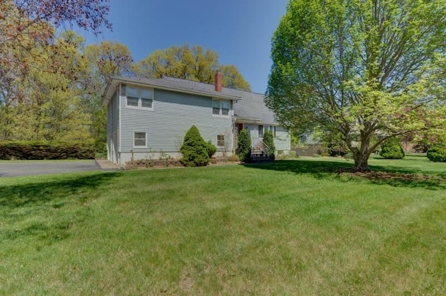 back of house featuring a chimney and a yard