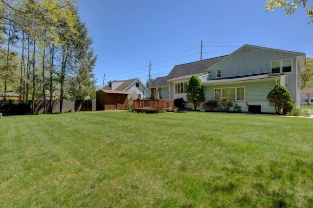 back of house featuring a lawn, an outdoor structure, a wooden deck, and a shed