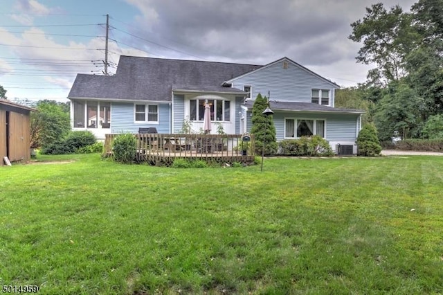 back of property featuring a yard, a deck, central AC, and a shingled roof