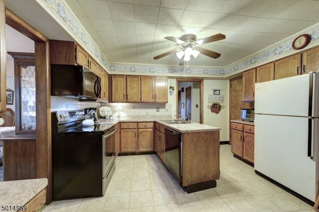 kitchen featuring brown cabinetry, a peninsula, ceiling fan, light countertops, and black appliances