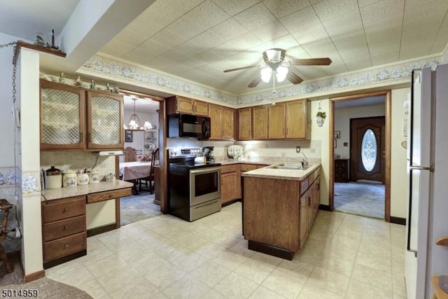 kitchen featuring electric range, black microwave, a sink, light countertops, and freestanding refrigerator