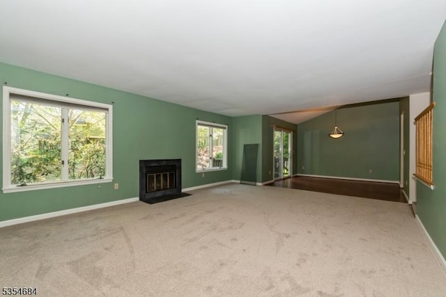 unfurnished living room with carpet flooring, baseboards, a fireplace with flush hearth, and a healthy amount of sunlight