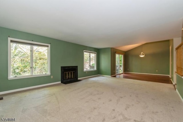 unfurnished living room with carpet floors, a fireplace with flush hearth, baseboards, and plenty of natural light