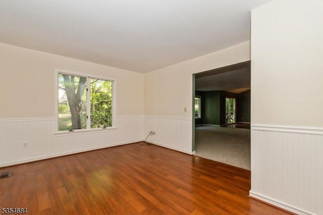 unfurnished room featuring wood finished floors and a wainscoted wall