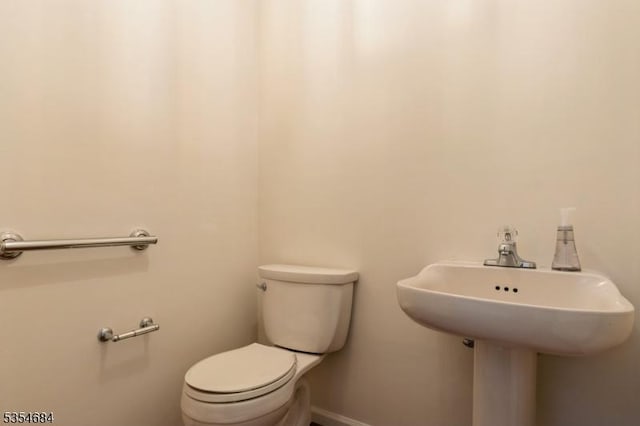 half bath with toilet, baseboards, and a sink